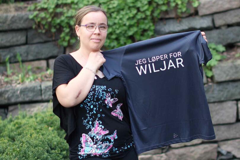 Katrin viser fram løpeskjorte med "Jeg løper for Wiljar" på ryggen
