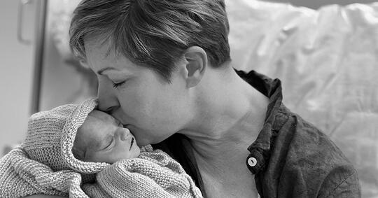En mamma kysser sitt nyfødte, døde barn.