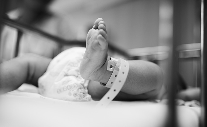 Utsnitt av nyfødt baby, ser en fot og bleie