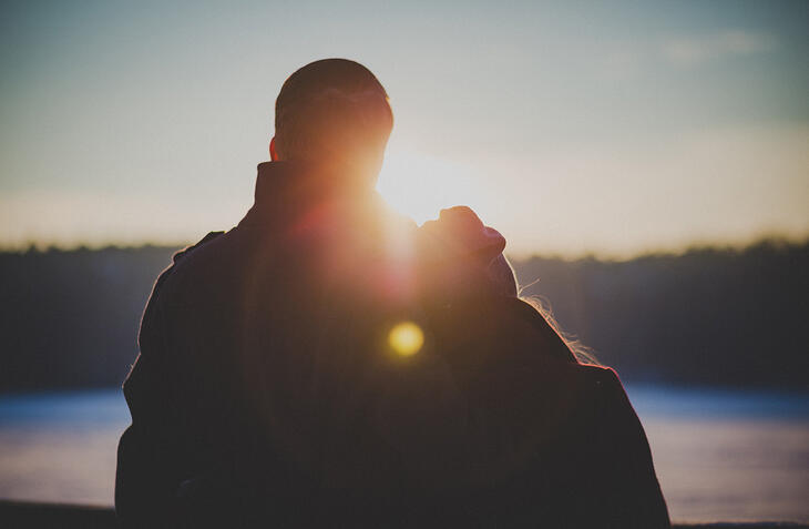 Et par står ved siden av hverandre i solnedgang