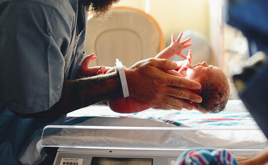 Lege holder nytfødt baby i hendene på sykehus