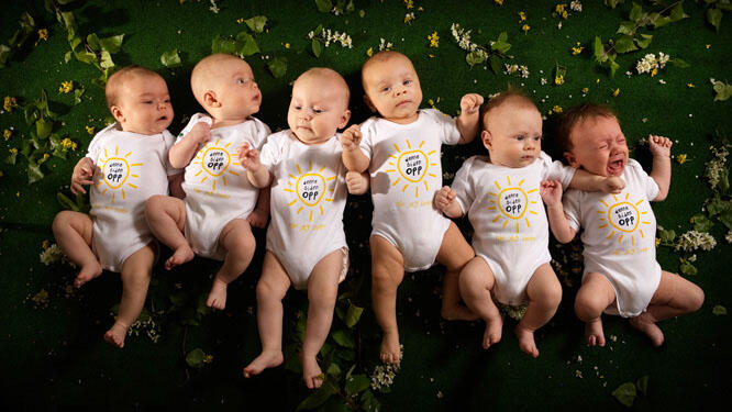 Seks babyer ligger ved siden av hverandre - alle med Denne siden opp-bodyer.