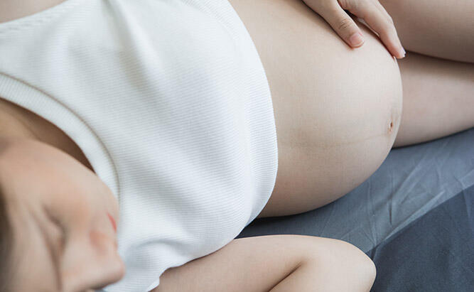Gravid kvinne sover på siden