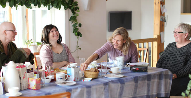 Fire kvinner prater og ler rundt lunsjbordet