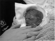 lite nyfødt barn som er dødt, holder rundt mors finger.