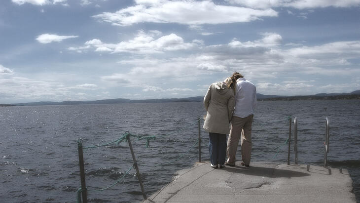 Mann og kvinne står tett ved siden av hverandre på en brygge.