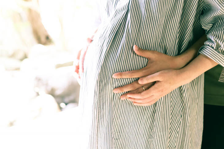 Foto av at to par hender holder på en gravid mage.